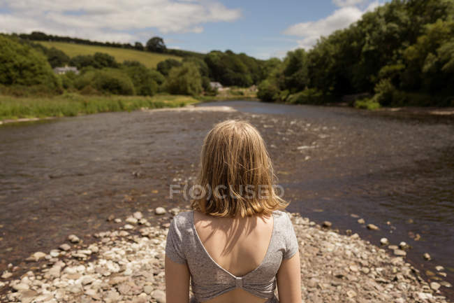 Visão traseira da mulher em pé perto do córrego no campo — Fotografia de Stock