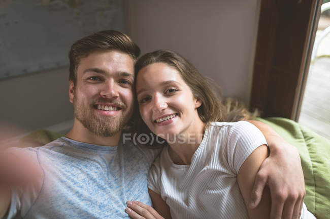Casal sentado junto com o braço em casa — Fotografia de Stock