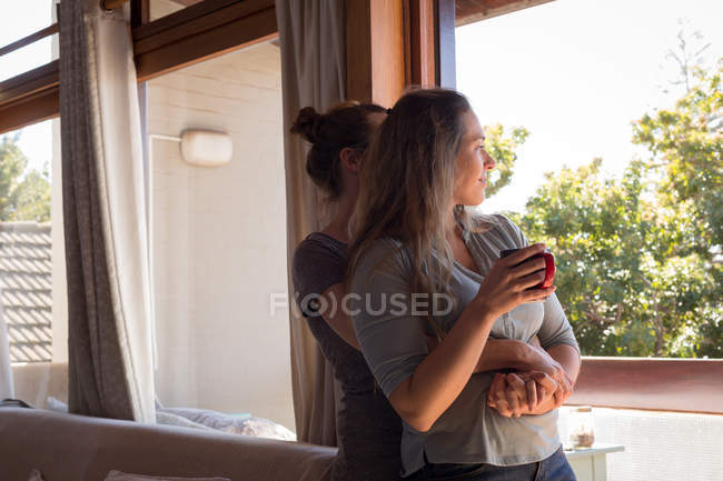 Lesbisches Paar umarmt sich im Wohnzimmer zu Hause — Stockfoto