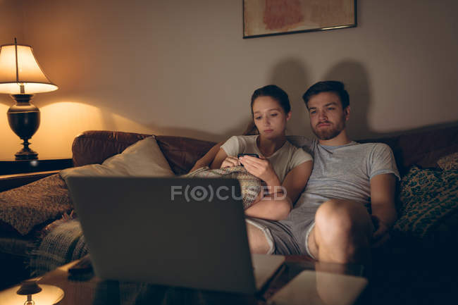 Pareja usando el ordenador portátil en la sala de estar en casa - foto de stock