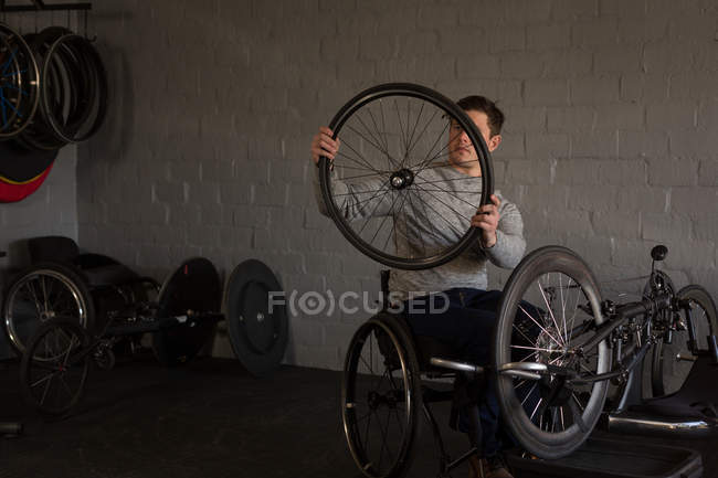 Jovem deficiente reparando cadeira de rodas na oficina — Fotografia de Stock