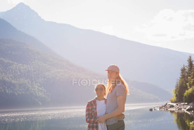 Couple debout près de la rivière dans les montagnes — Photo de stock