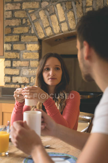 Пара взаємодіє один з одним, маючи каву вдома — стокове фото