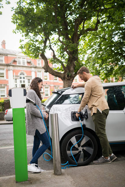 Couple recharge voiture électrique à la station de recharge — Photo de stock