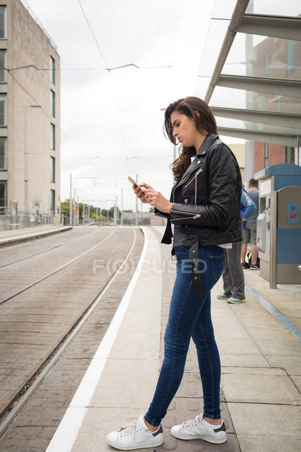 Mulher usando telefone celular na plataforma na estação ferroviária — Fotografia de Stock