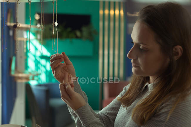 Young female customer looking at jewelry in boutique shop — Stock Photo