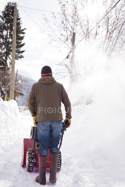 Visão traseira do homem usando máquina de ventilador de neve na região nevada — Fotografia de Stock