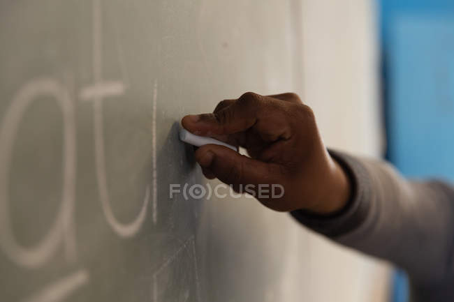 Male teacher explaining on chalkboard in classroom — Stock Photo