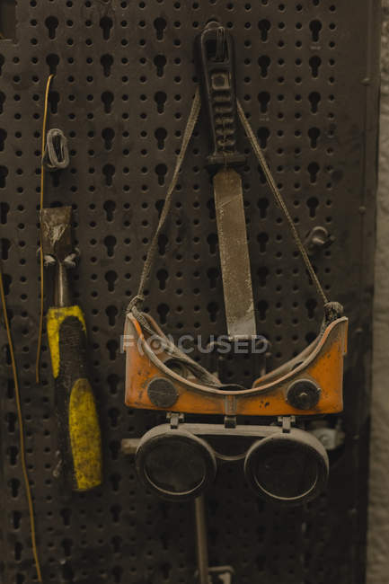 Крупный план защитных очков и инструментов в гараже — стоковое фото