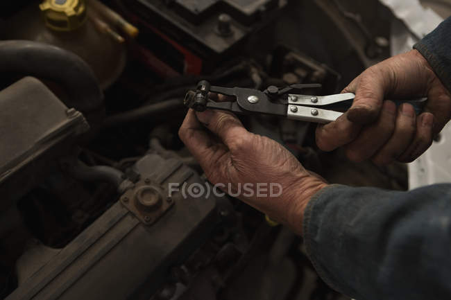 Gros plan du mécanicien masculin qui entretient une voiture dans un garage — Photo de stock