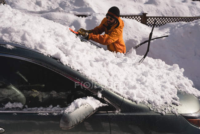 Чоловік прибирає сніг з автомобільного лобового скла взимку — стокове фото