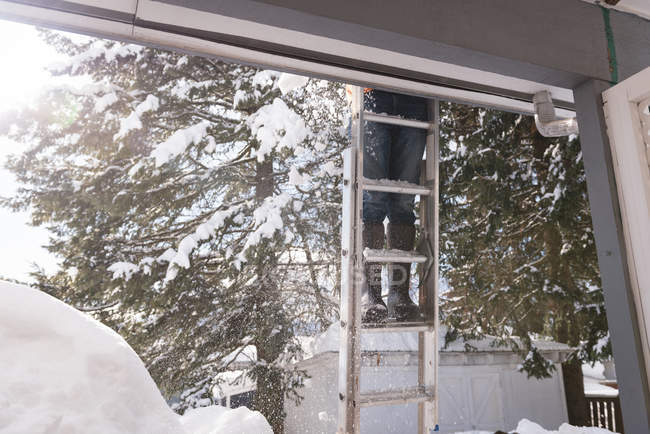 Homem limpando neve do telhado de sua loja durante o inverno — Fotografia de Stock