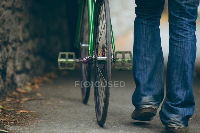 Baixa seção de homem andando com bicicleta na calçada — Fotografia de Stock