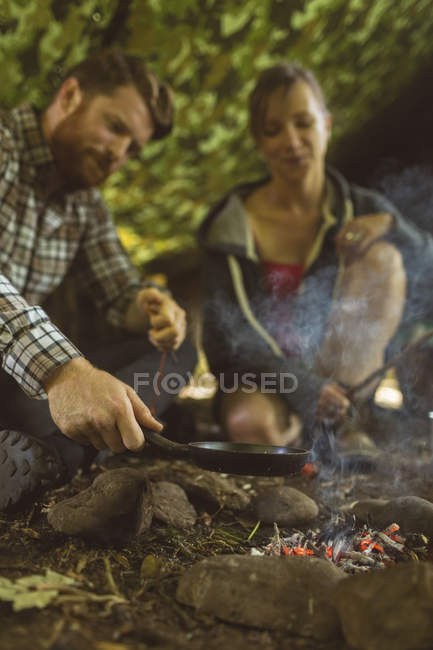Casal feliz preparando comida no acampamento — Fotografia de Stock