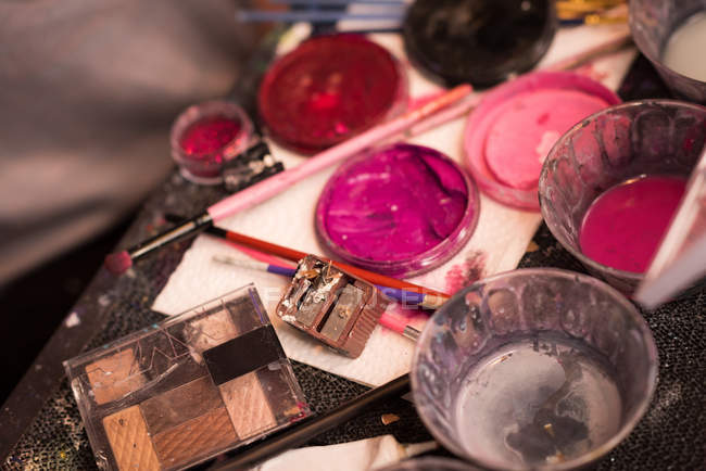 Primer plano de varias pinturas y cajas de maquillaje mantenidas en la mesa - foto de stock
