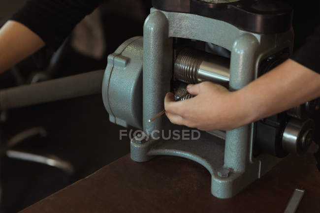 Sección media del diseñador de joyas usando una máquina en el taller - foto de stock