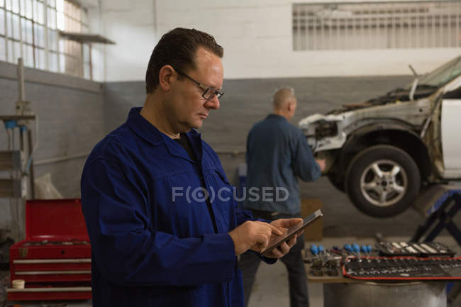 Side view of male mechanic using digital tablet in garage — Stock Photo