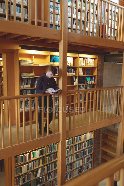 Внимательный студент колледжа читает книгу в библиотеке — стоковое фото