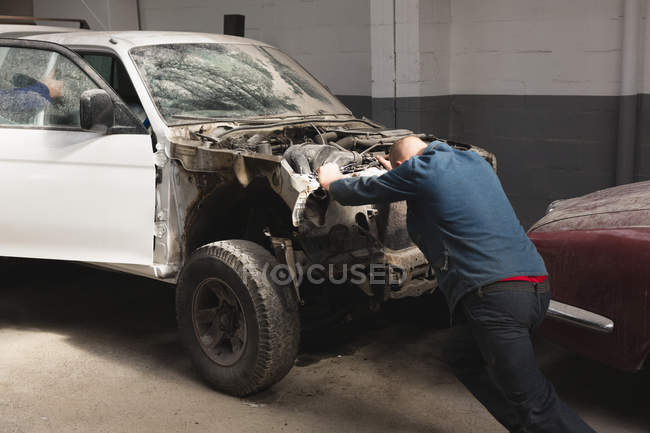 Rear view of mechanic pushing car in garage — Stock Photo