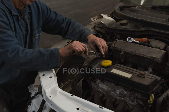 Sección media del mecánico masculino servicio de un coche en el garaje - foto de stock