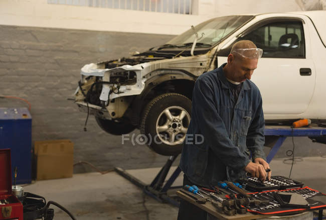 Mechaniker sucht Werkzeug in Garage aus — Stockfoto