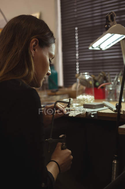 Atento diseñador de joyas haciendo joyas en el taller - foto de stock