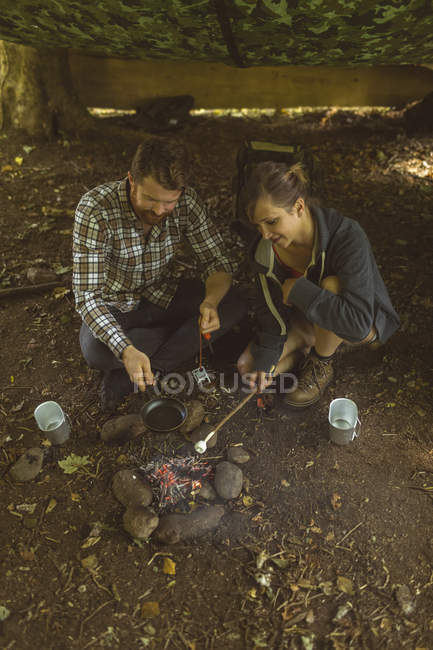 Casal feliz preparando comida no acampamento — Fotografia de Stock