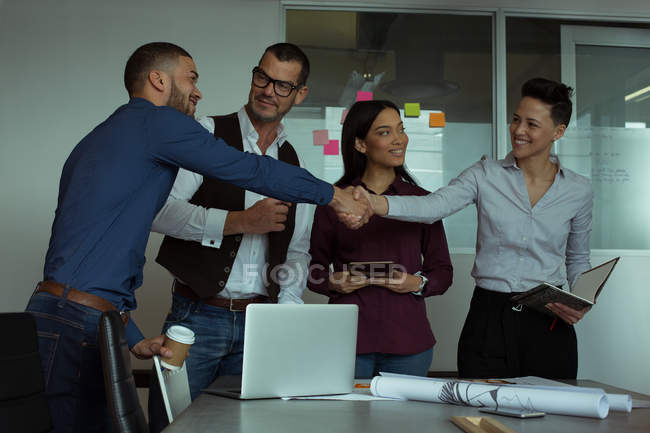 Smiling executives interacting with each other in office — Stock Photo