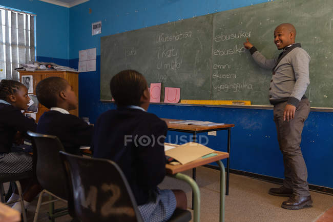 Enseignant masculin enseignant aux élèves de la classe à l'école — Photo de stock