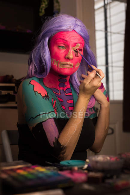 Woman painting her face with brush for halloween celebration — Stock Photo
