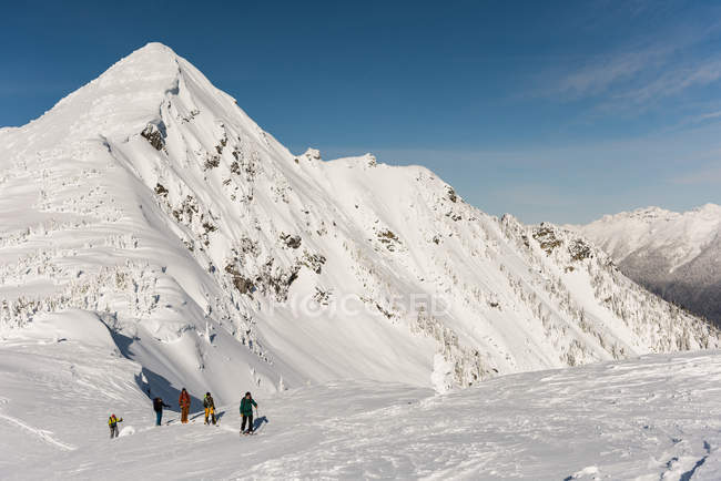 Группа лыжников, идущих на снежную гору зимой — стоковое фото