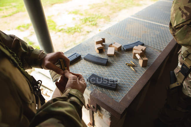 Soldados militares cargando balas en la revista durante el entrenamiento militar - foto de stock