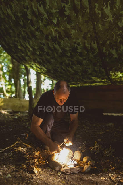 Ajuste o homem acendendo fogo no acampamento de inicialização — Fotografia de Stock