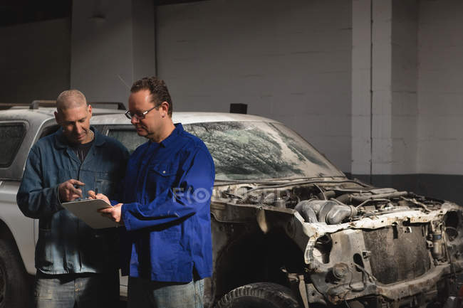 Mecânica discutindo sobre prancheta na garagem — Fotografia de Stock