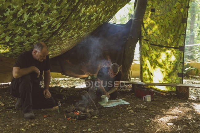 Ajuste hombres encendiendo fuego en el campamento de arranque - foto de stock