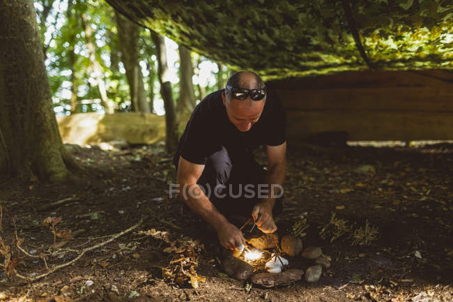 Fit man lighting fire at boot camp — Stock Photo