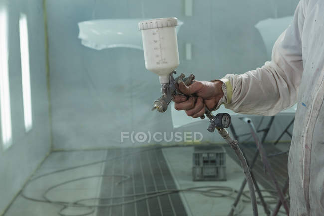 Mecánico masculino usando pintura en aerosol en garaje - foto de stock