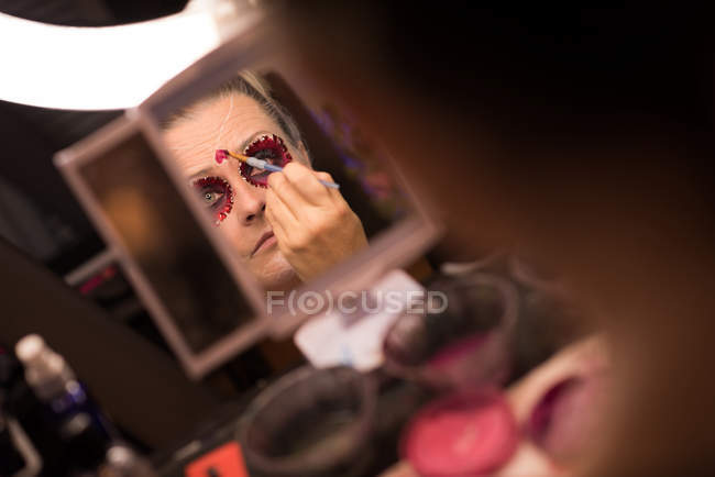 Frau bemalt ihr Gesicht mit Pinsel für Halloween-Feier — Stockfoto