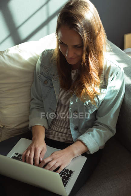 Créatrice de bijoux utilisant un ordinateur portable à la maison — Photo de stock