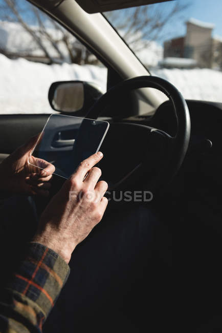 Mann benutzt im Winter digitales Tablet aus Glas im Auto — Stockfoto