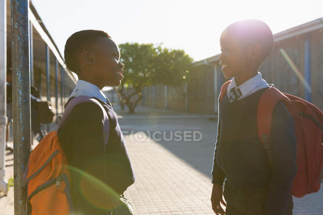 Estudantes olhando uns para os outros no campus da escola em um dia ensolarado — Fotografia de Stock