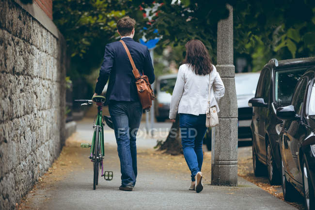Rear view of business colleagues walking on sidewalk in city — Stock Photo