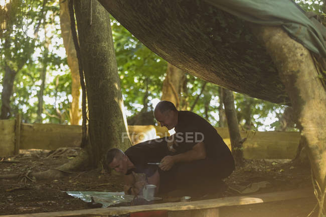 Двое здоровых мужчин смотрят на карту в ботинковом лагере — стоковое фото
