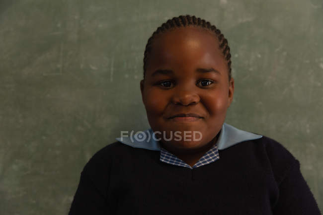 Schoolgirl standing near chalkboard in classroom at school — Stock Photo