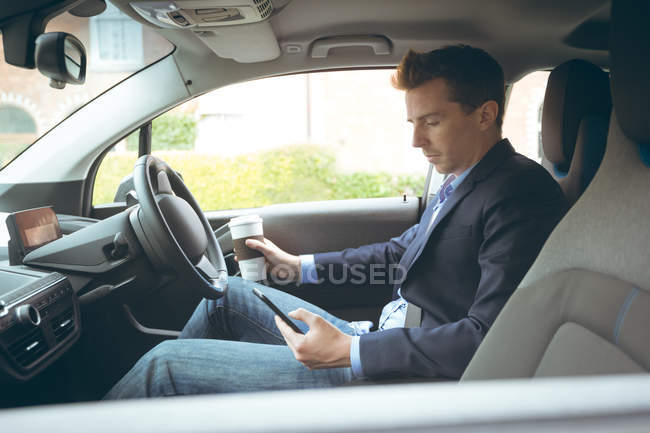Смарт-бізнесмен використовує мобільний телефон під час водіння автомобіля — стокове фото
