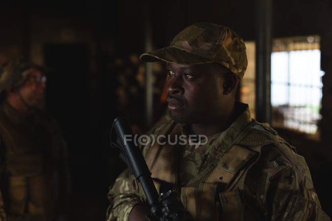 Військовослужбовець стоїть з гвинтівкою під час військової підготовки у військовому таборі — стокове фото