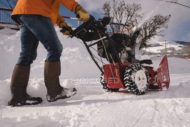 Homem usando máquina de ventilador de neve na região nevada durante o inverno — Fotografia de Stock