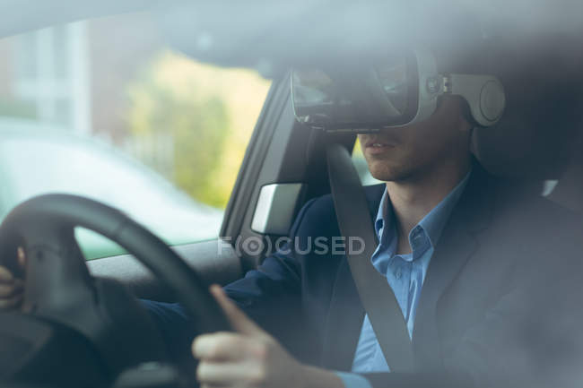 Homme d'affaires intelligent utilisant casque de réalité virtuelle tout en conduisant une voiture — Photo de stock