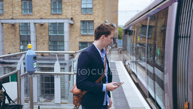 Young businessman using mobile phone at railway station — Stock Photo