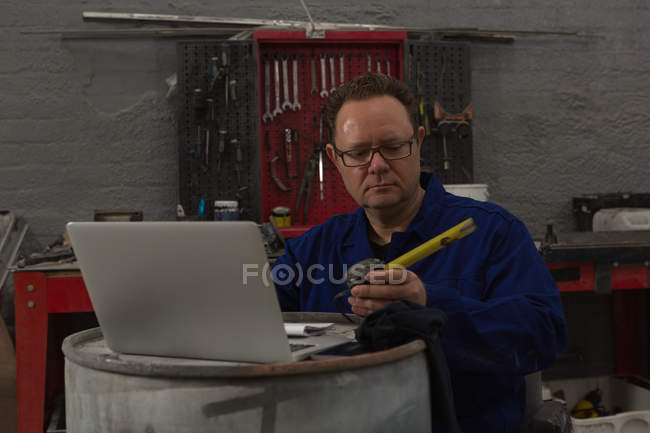 Mecánico masculino usando portátil en el garaje - foto de stock